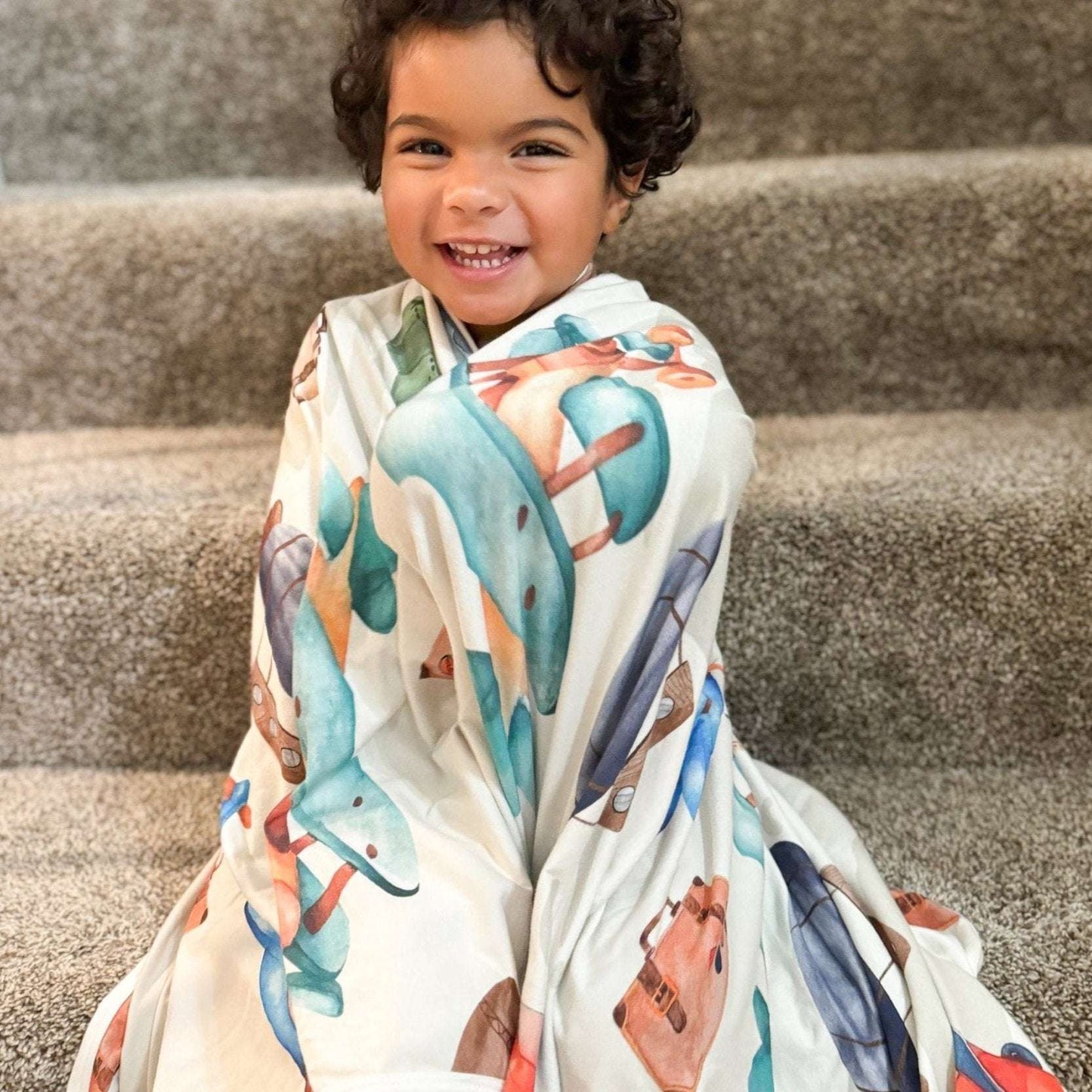 Toddler in our multi-purpose blanket. Can be used as Swaddle Blanket, Toddler Blanket, Baby Blanket, and stretch swaddle blanket in Vintage Travel Print by CARLOMAR